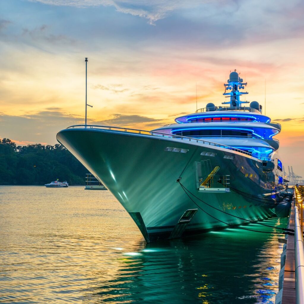 Luxury yacht docked at sunset, showcasing vibrant LED lighting and sleek design, representing TESS Electrical's marine repair and refit services.