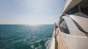 Yacht sailing on tranquil waters under bright sunlight, showcasing luxury and elegance, relevant to marine electrical systems and safety services.