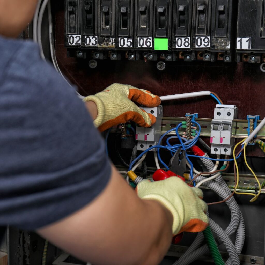 Marine electrician working on yacht electrical panel, inspecting circuit breakers and wiring connections for maintenance and upgrades.
