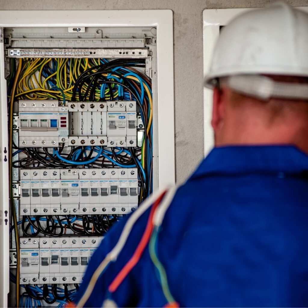 Marine electrician inspecting electrical panel with circuit breakers and wiring, emphasizing electrical safety measures for yachts.
