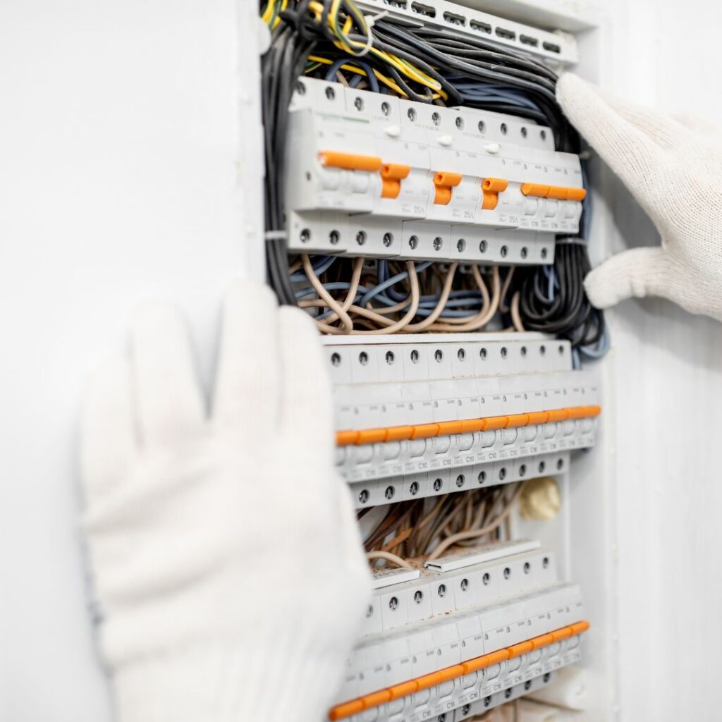 Hands in white gloves adjusting electrical panel with circuit breakers and wiring, illustrating electrical safety measures for yachts.
