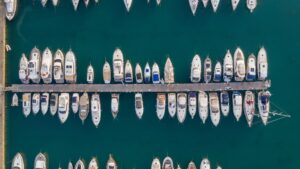 Aerial view of a marina in Savannah, GA, featuring numerous yachts and boats docked along a wooden pier, highlighting the importance of marine electrical systems for vessel maintenance.