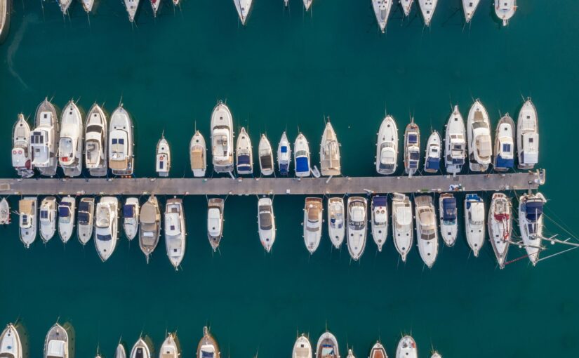 Aerial view of a marina in Savannah, GA, showcasing multiple boats docked along a pier, emphasizing the importance of marine electrical systems for yacht maintenance.