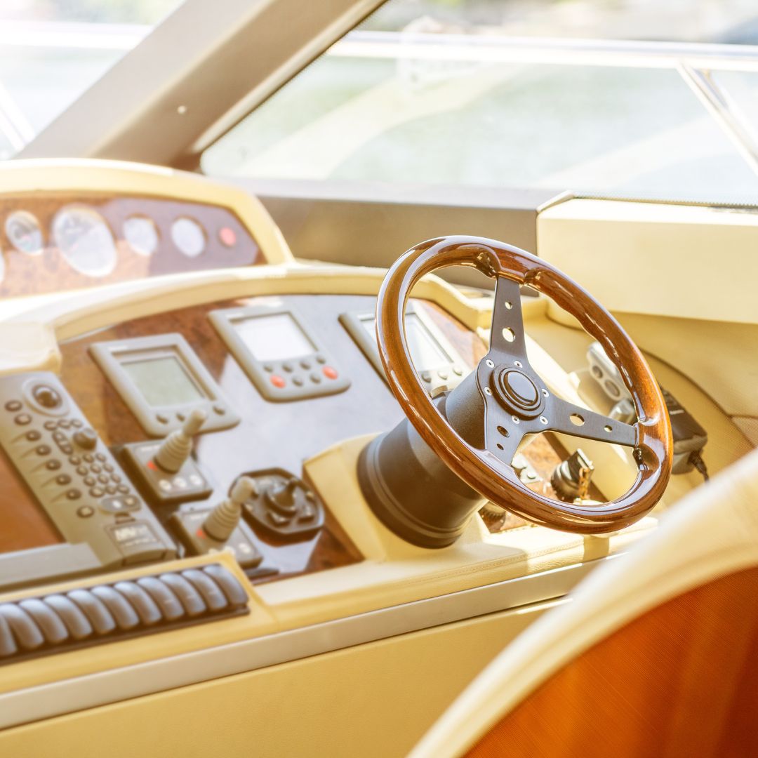 Yacht control panel featuring a wooden steering wheel, digital displays, and marine electrical controls, illustrating TESS Electrical LLC's expertise in yacht electrical installation and design services.