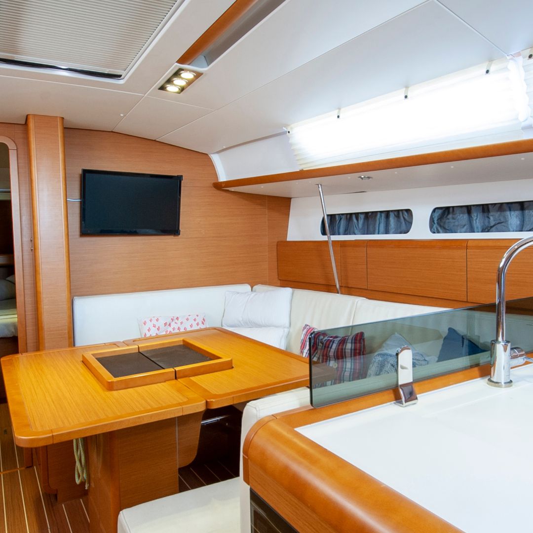 Interior of a modern yacht featuring a dining area with a wooden table, white leather seating, and a flat-screen TV, highlighting potential upgrades for entertainment systems in Savannah.