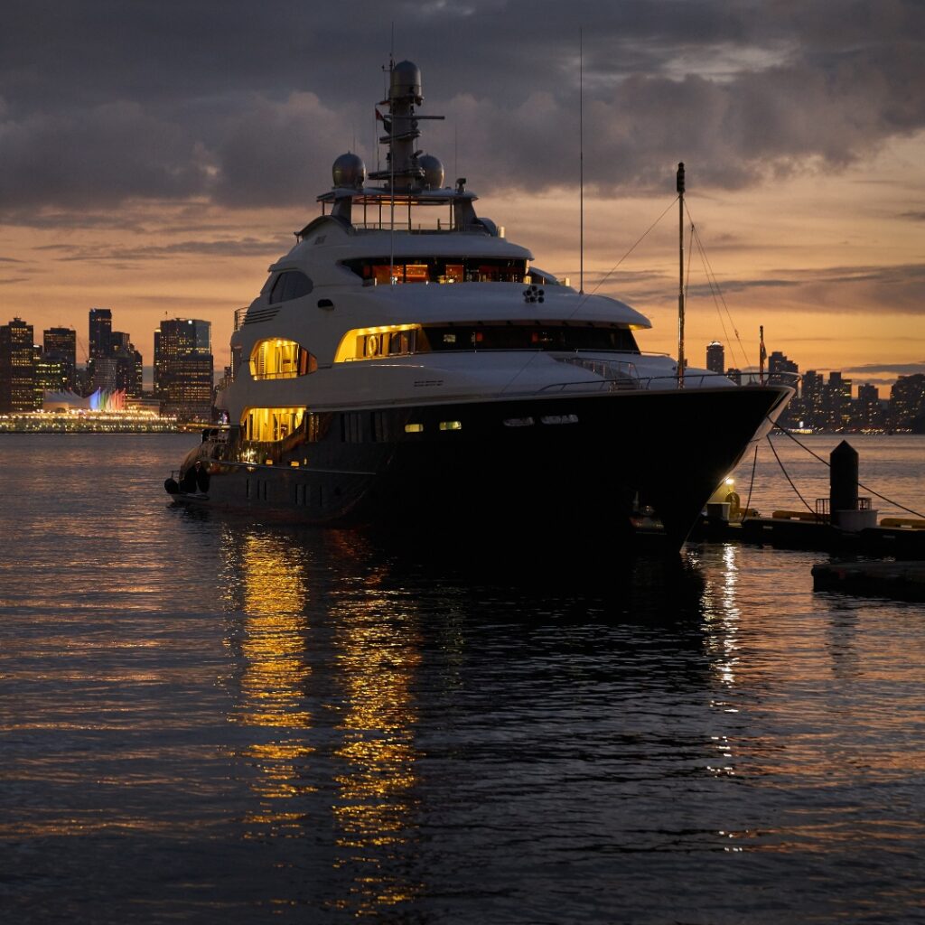 Luxury yacht docked at sunset in Savannah, showcasing illuminated features and reflecting lights on the water, emphasizing the importance of reliable power solutions like Magnus Shore Power Converter for optimal vessel performance.