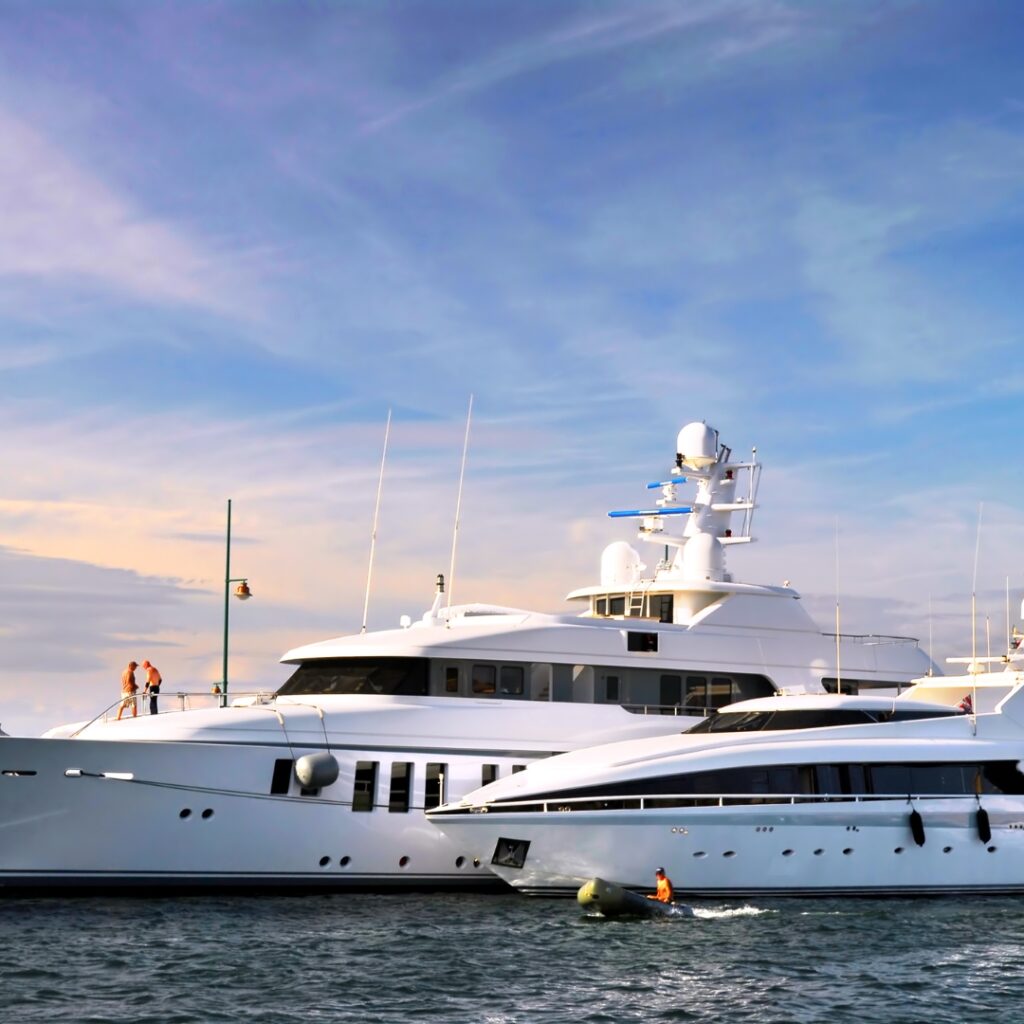 Luxury yachts docked in Savannah waters with two people on the deck and a small boat navigating nearby, highlighting marine leisure and power solutions for vessels.