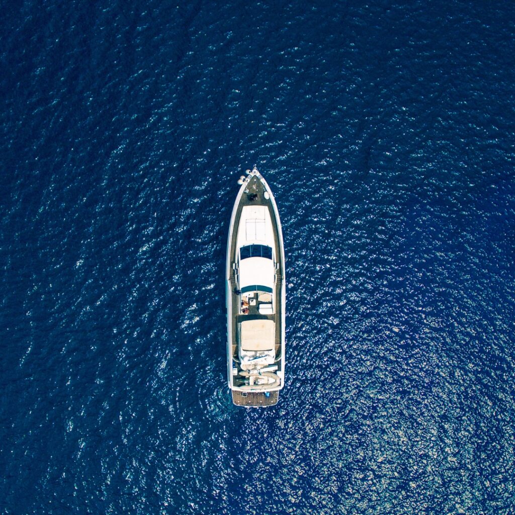 Aerial view of a vessel on deep blue water, illustrating the importance of Magnus Shore Converters for improved fuel efficiency and battery life in marine electrical systems.