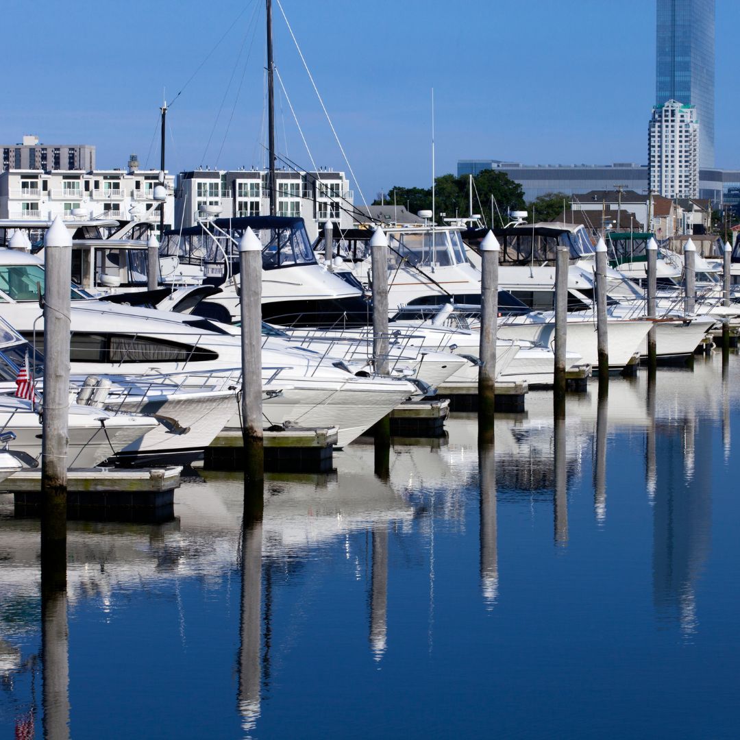 Marina with yachts docked along wooden pilings, reflecting in calm waters, showcasing the scenic environment ideal for yacht services on the Amalfi Coast.