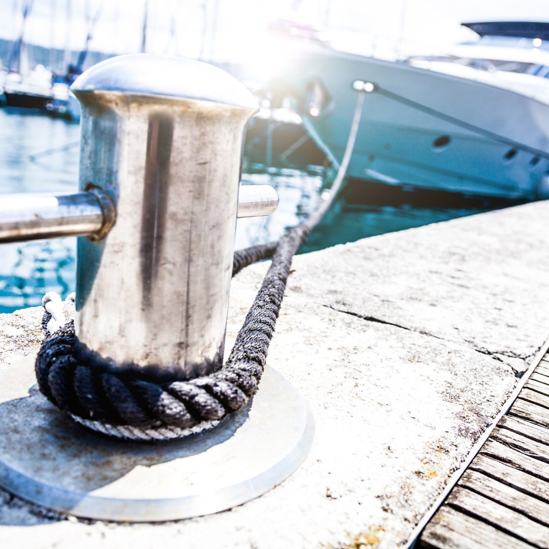 Stainless steel mooring cleat with rope secured at a marina in Barcelona, symbolizing reliable yacht docking and electrical service integration by TESS, LLC.