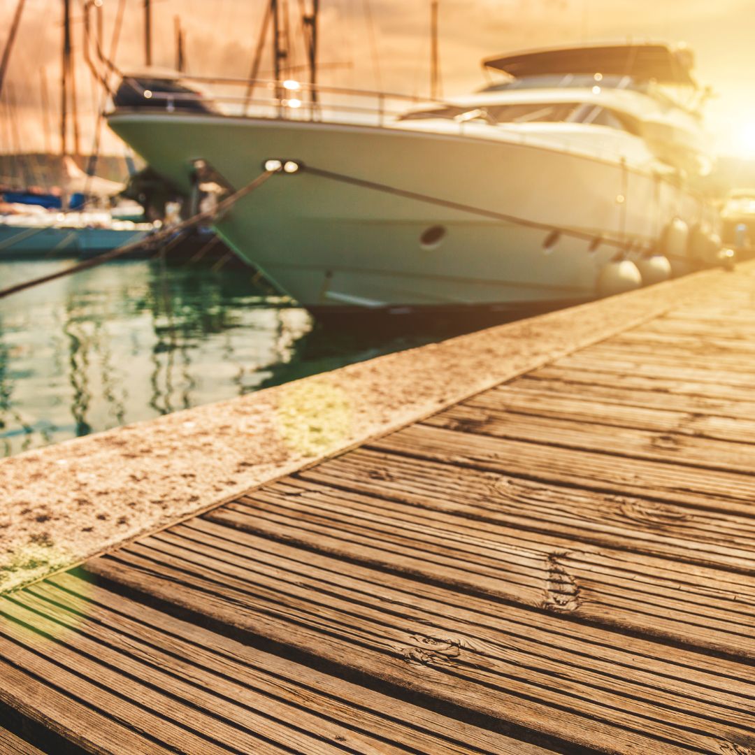 Luxury yacht docked in Monaco harbor with sunlit wooden pier, showcasing premier yachting lifestyle and electrical service potential.