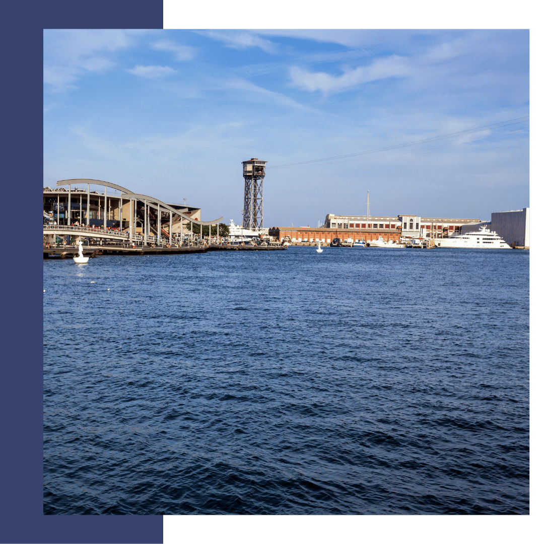 Barcelona marina view with yachts, waterfront buildings, and a tower, representing TESS Electrical LLC's marine services.