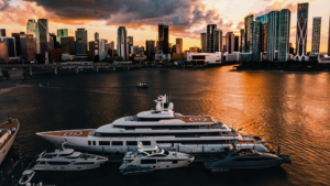 Luxury yachts docked in a city marina at sunset, showcasing the skyline and reflecting Tess Electrical's marine services and expertise in yacht electrical solutions.